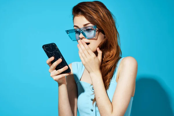 Красивая женщина в синих очках с телефоном в руках технологии связи изолированный фон — стоковое фото
