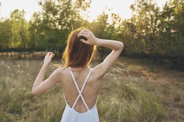 Porträt einer glücklichen Frau in einer Sonnenbekleidung in einem Feldjahr von hinter Bäumen Sonnenuntergang — Stockfoto