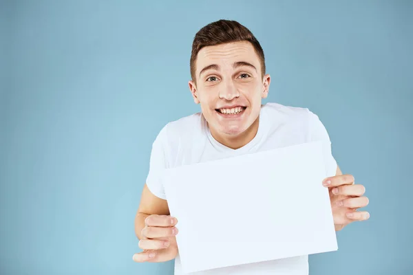 Man met een vel papier in zijn handen wit t-shirt bijgesneden uitzicht blauwe achtergrond — Stockfoto