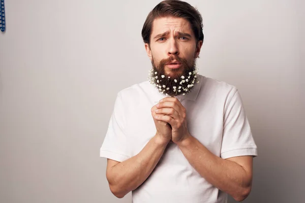 man in a white shirt and can flowers in a beard decoration light background