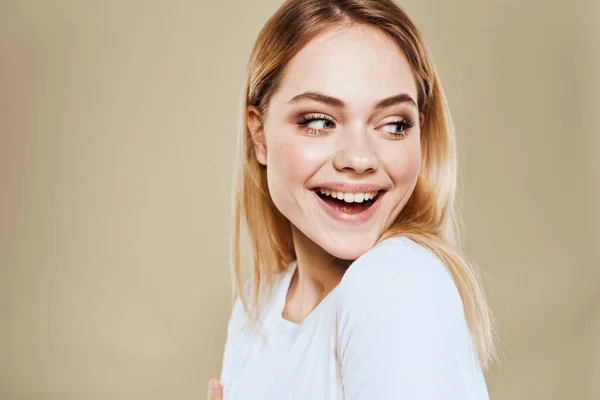 Mujer rubia alegre en una camiseta blanca gestos con sus emociones de la mano fondo beige —  Fotos de Stock