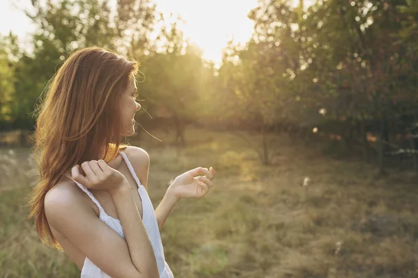 Ελκυστική γυναίκα σε ένα λευκό φόρεμα ήλιο αναπαύεται στη φύση στο ηλιοβασίλεμα — Φωτογραφία Αρχείου