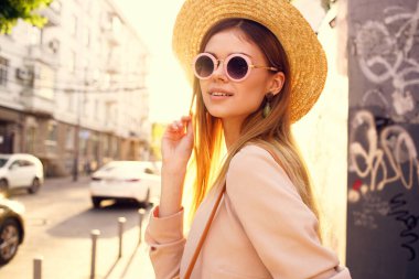 Güneş gözlüklü güzel bir kadın açık havada yürüyor.