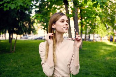 Güneş gözlüğü takan güzel bir kadın yeşil çimen manzaralı temiz hava.