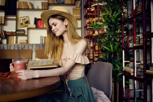 Şapkalı kadın, kafede oturup kitap okuyarak tatil yapıyor.