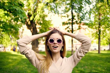 Parkta güneş gözlüklü neşeli bir kadın.