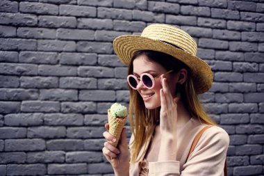 Güneş gözlüğü takan ve şapka takan kadın şehir tarzı tuğla duvar.