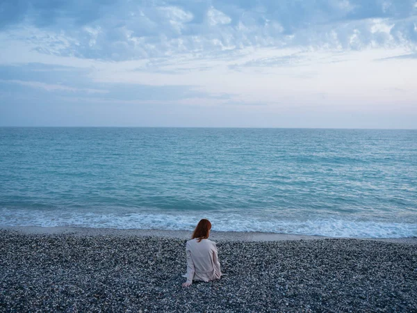 Femme assise sur le bord de la mer et nuages ciel bleu vue arrière — Photo