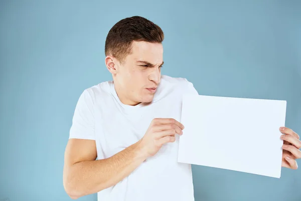 Homme tenant une feuille de papier dans ses mains blanc t-shirt recadré vue fond bleu — Photo