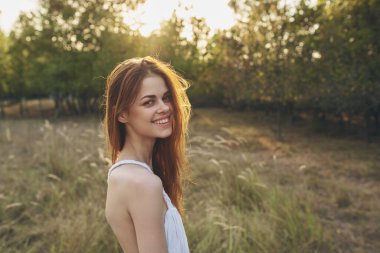 Uzun ağaçların ve kuru otların arasındaki bir tarlada mutlu bir gezgin.