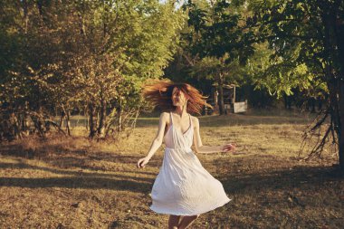 Sonbaharda ağaçların yanında beyaz elbiseli mutlu bir kadın.