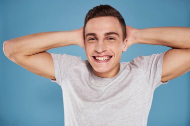 Beyaz tişörtlü sevimli adam elleri mavi arka planda.