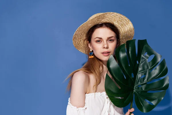 Kvinna i hatt palm löv i händerna lyx exotisk blå bakgrund — Stockfoto