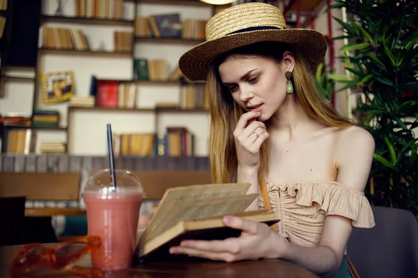 Hübsche Frau mit Hut und Buch in der Hand liest Urlaub im Café — Stockfoto