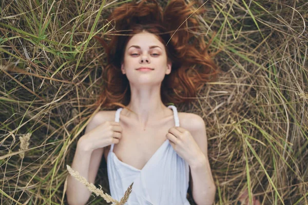 Mujer feliz en vestido blanco se encuentra en la hierba seca en la naturaleza vista superior —  Fotos de Stock