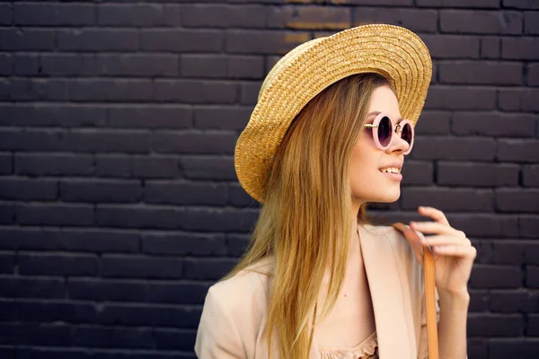 Femme élégante en lunettes de soleil sur un fond de brique de style urbain promenade de rue — Photo