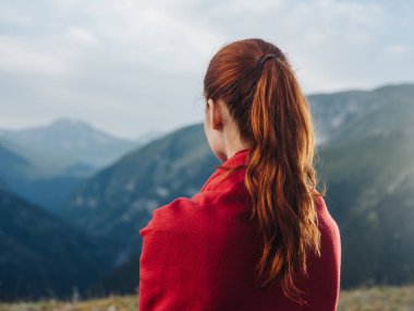 Dağlarda omuzlarında kırmızı bir ekoseli kadın gezgin.
