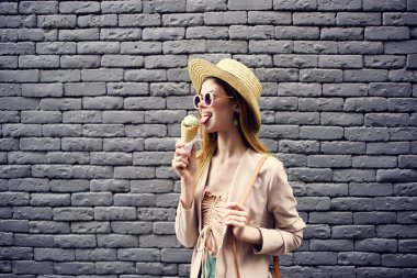 Dondurmalı şapkalı bir kadın, tuğla duvarın arkasında.