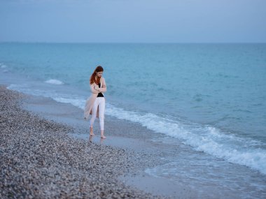 Okyanus kıyısındaki sahildeki kadın şeffaf süveter modeli.