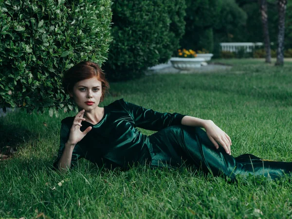 Gyönyörű nő zöld ruhában a szabadban fekszik a fű gótikus stílusú álarcosbáj — Stock Fotó