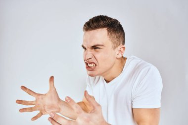 Duygusal adam elleri ile jestler hoşnutsuz beyaz tişört ışıklı arka plan