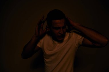 Duygusal adam elleri ile jestler hoşnutsuz beyaz tişört ışıklı arka plan