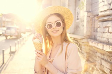 Açık havada şapkalı neşeli güzel kadın ve şehirde yürüyen dondurma.