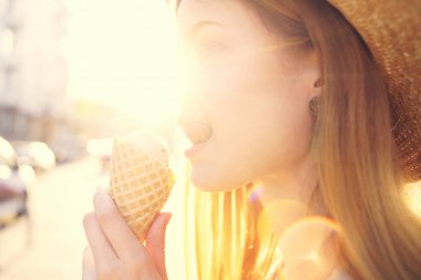 Kadın dışarıda dondurma yiyor, güneşli gündüzleri yürüyor.