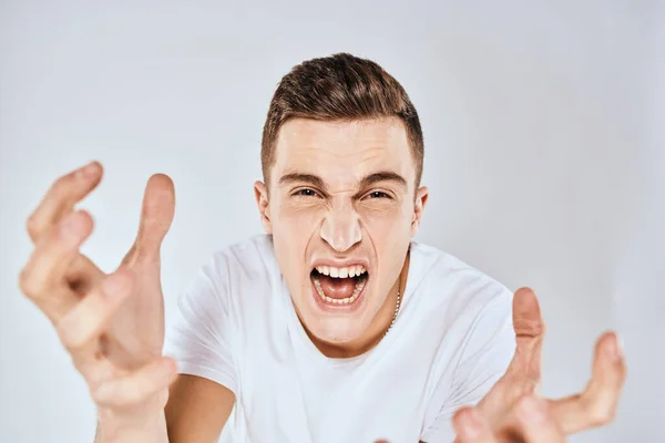Man in white t-shirt displeased facial expression gesturing with hands studio lifestyle — Stock Photo, Image