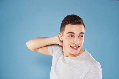 Beyaz tişörtlü sevimli adam elleri mavi arka planda.