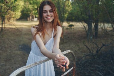 Bahçedeki demir bir yatağa yaslanmış bir demet üzümle mutlu bir kadın.