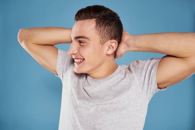 Beyaz tişörtlü sevimli adam elleri mavi arka planda.