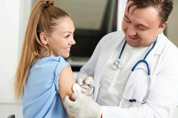 Man läkare i en vit rock injicerar ett vaccin i patienterna hand covid vaccination — Stockfoto