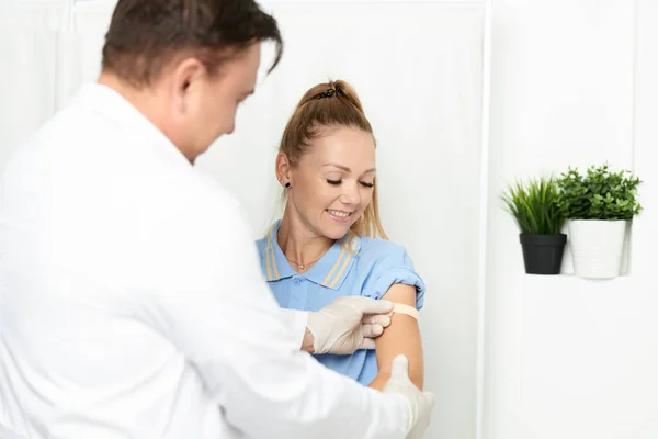 Médico masculino em um casaco branco sela sua mão com gesso adesivo — Fotografia de Stock