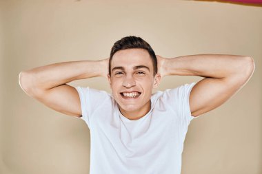 Sevimli duygusal adam beyaz tişört jesti elleri kırpılmış bej renkli stüdyo arka planı