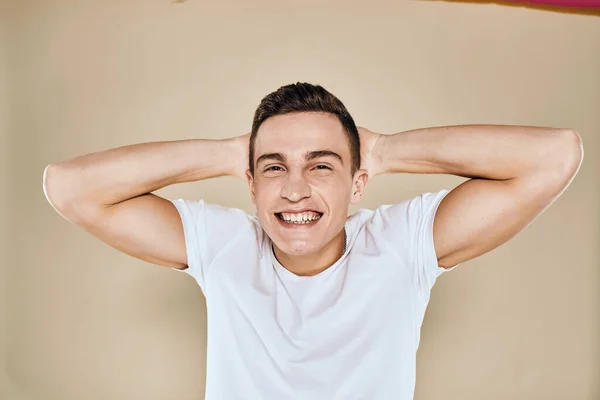 Bonito homem emocional branco t-shirt gesto com as mãos recortadas vista bege estúdio fundo — Fotografia de Stock