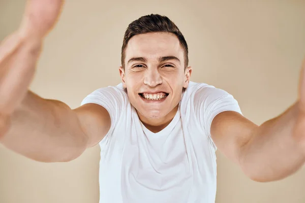 Söt känslomässig man vit t-shirt gest med händerna beskuren vy beige studio bakgrund — Stockfoto