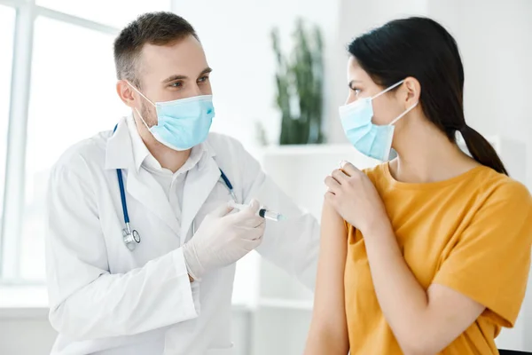 Un assistente di laboratorio in abito medico tiene in mano una siringa e un paziente vaccinato — Foto Stock