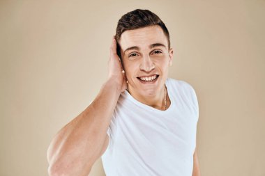 Sevimli duygusal adam beyaz tişört jesti elleri kırpılmış bej renkli stüdyo arka planı