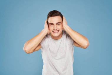 Beyaz tişörtlü neşeli bir adam elleri ve duyguları mavi arka planda hareket ediyor.