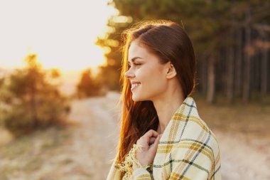 Kadın kozalaklı orman yolunda ekoseli gülüşün yanında.
