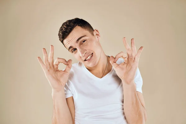 Mignon émotionnel homme blanc t-shirt geste avec les mains vue recadrée beige studio fond — Photo