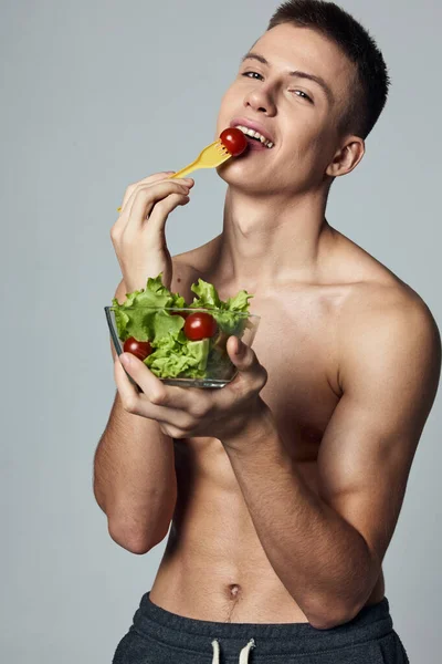 Vrolijke sportieve man met een naakte romp plaat met salade eten workout — Stockfoto