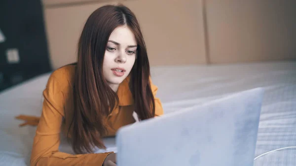 Vrouw in de slaapkamer ligt in bed voor een laptop internet technologie werken — Stockfoto