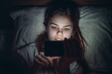 Kadın geceleri elinde telefonla yataktan çıkıyor. Sanal odada dinleniyor.