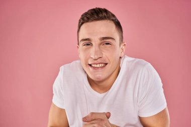 Beyaz tişörtlü neşeli adam gülümse duygular yakın plan pembe arka plan stüdyosu