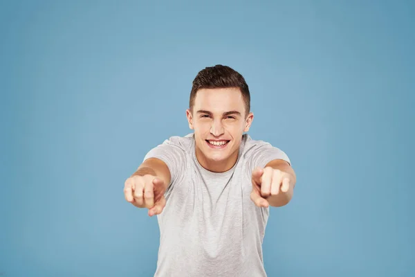 Homem alegre em uma camiseta branca gesticulando com as mãos emoções fundo azul — Fotografia de Stock