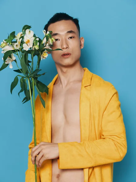 セクシーな男とともに裸体上の青背景とA黄色のコートとともに花の花束でザ休日プレゼント — ストック写真