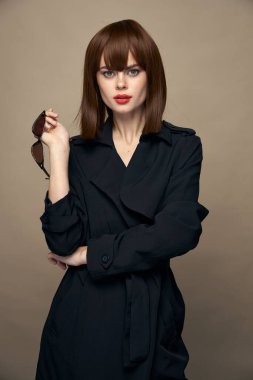 Seksi kadın elinde gözlük tutuyor. Siyah ceketli.