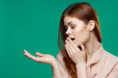 Pembe tişörtlü neşeli güzel kadın elini duygularının önünde tutuyor yeşil arka plan